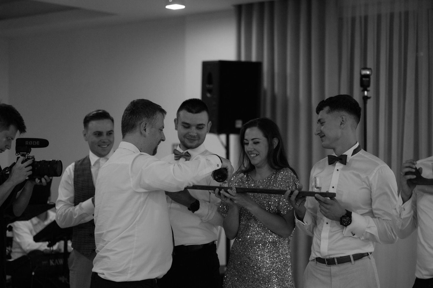 A group of people in formal attire enjoying themselves at a celebration party in black and white.