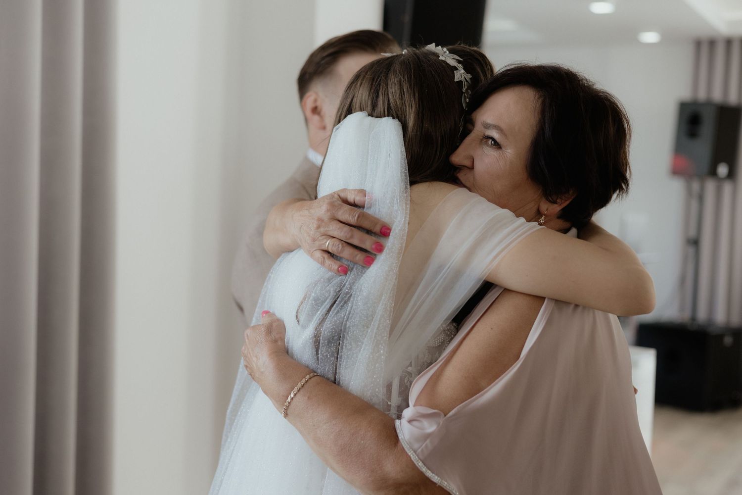People embrace warmly in a tender hug in a bright indoor setting.