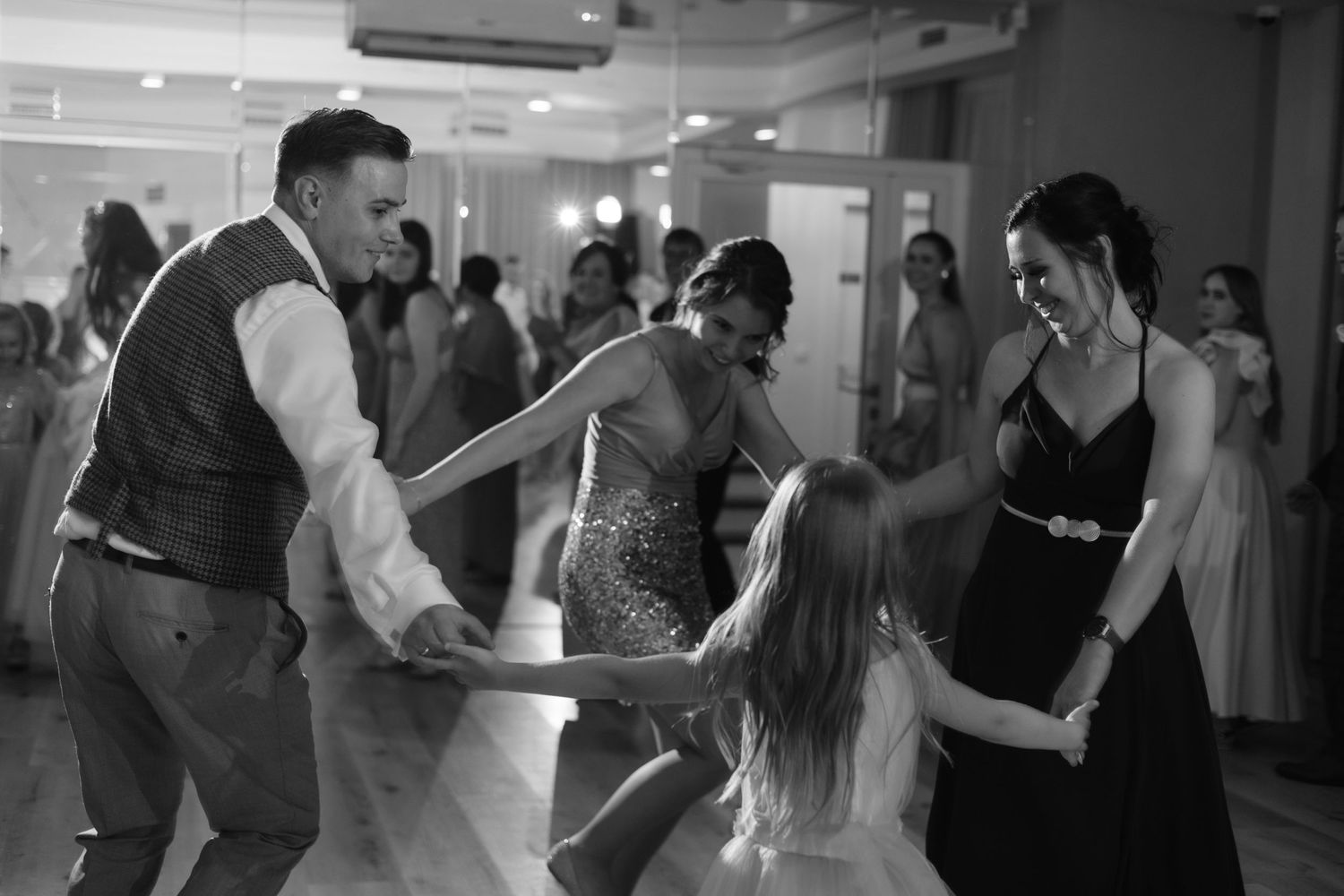 Wedding guests dance enthusiastically together on the dance floor during a reception celebration.