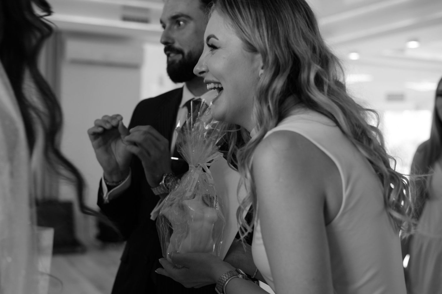 A joyful wedding celebration moment captured in black and white as people mingle at the reception.
