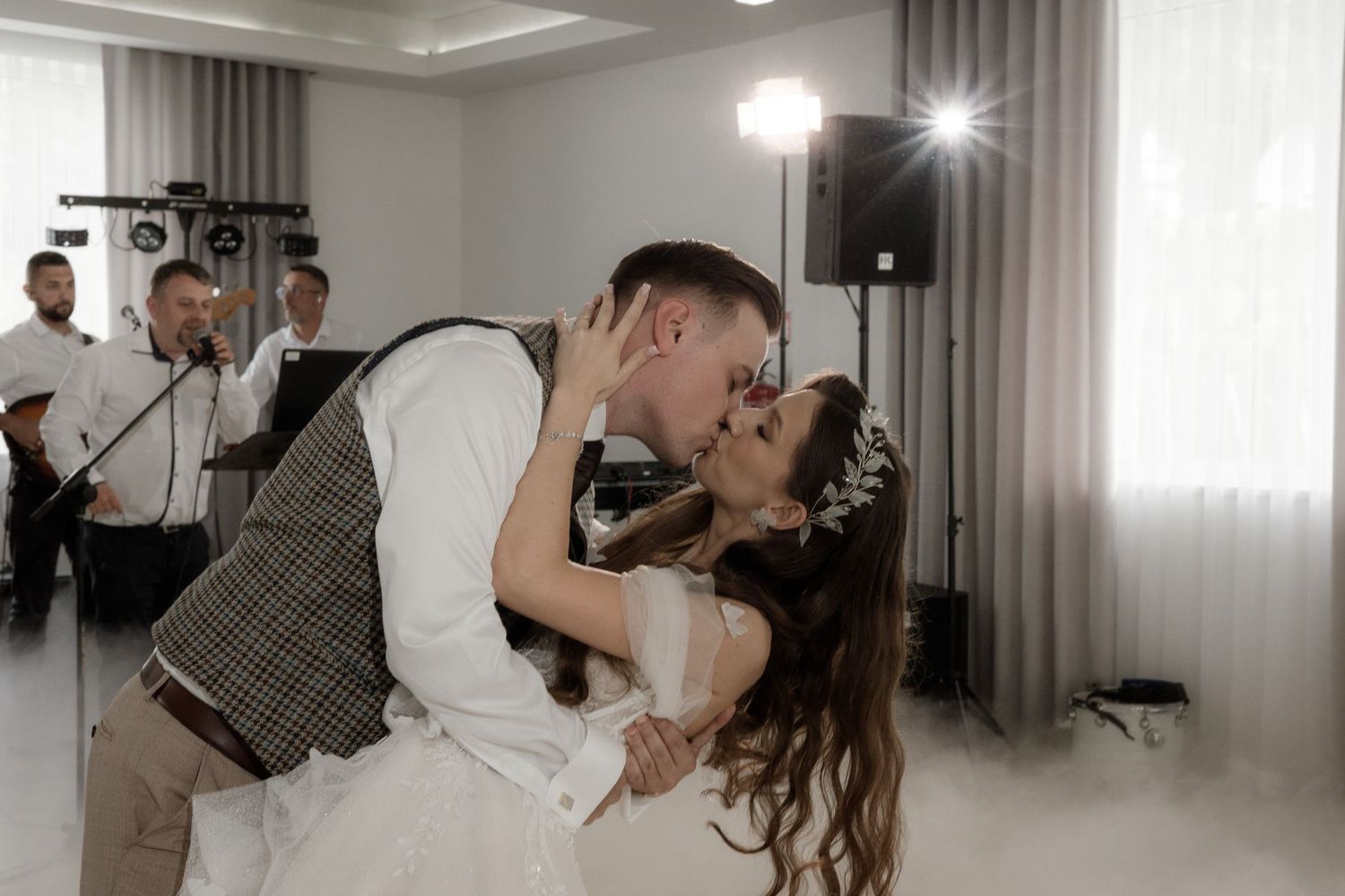 A romantic moment captured on the dance floor with a band playing in the background at an indoor celebration.