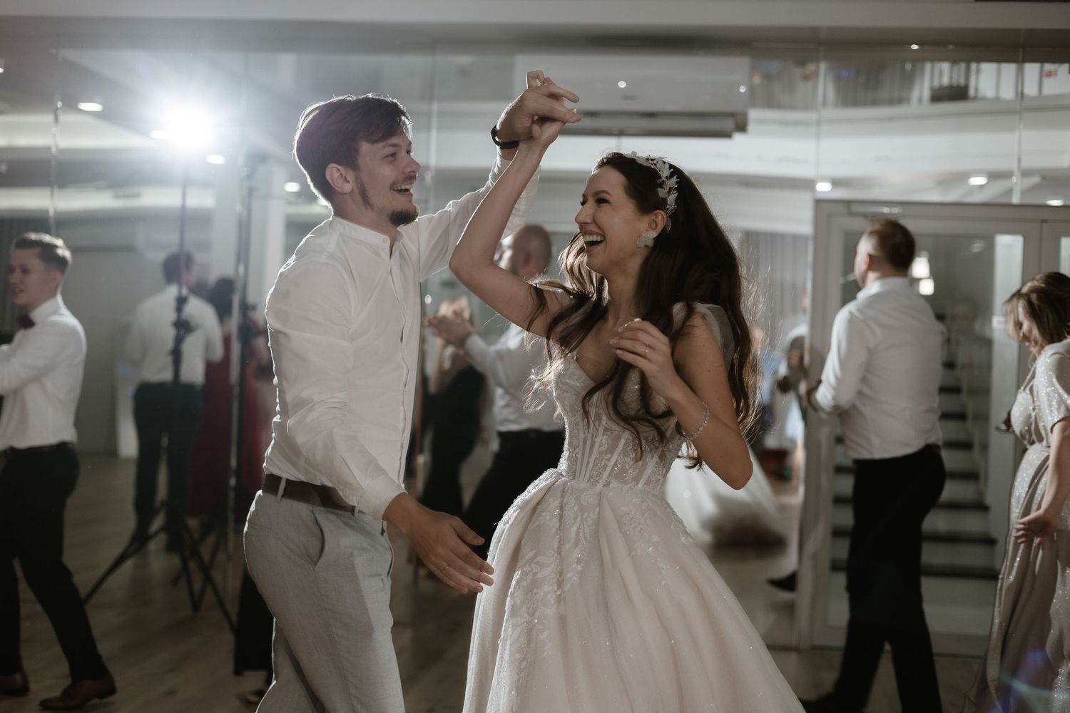 A couple joyfully dancing together during a wedding reception in an indoor venue.