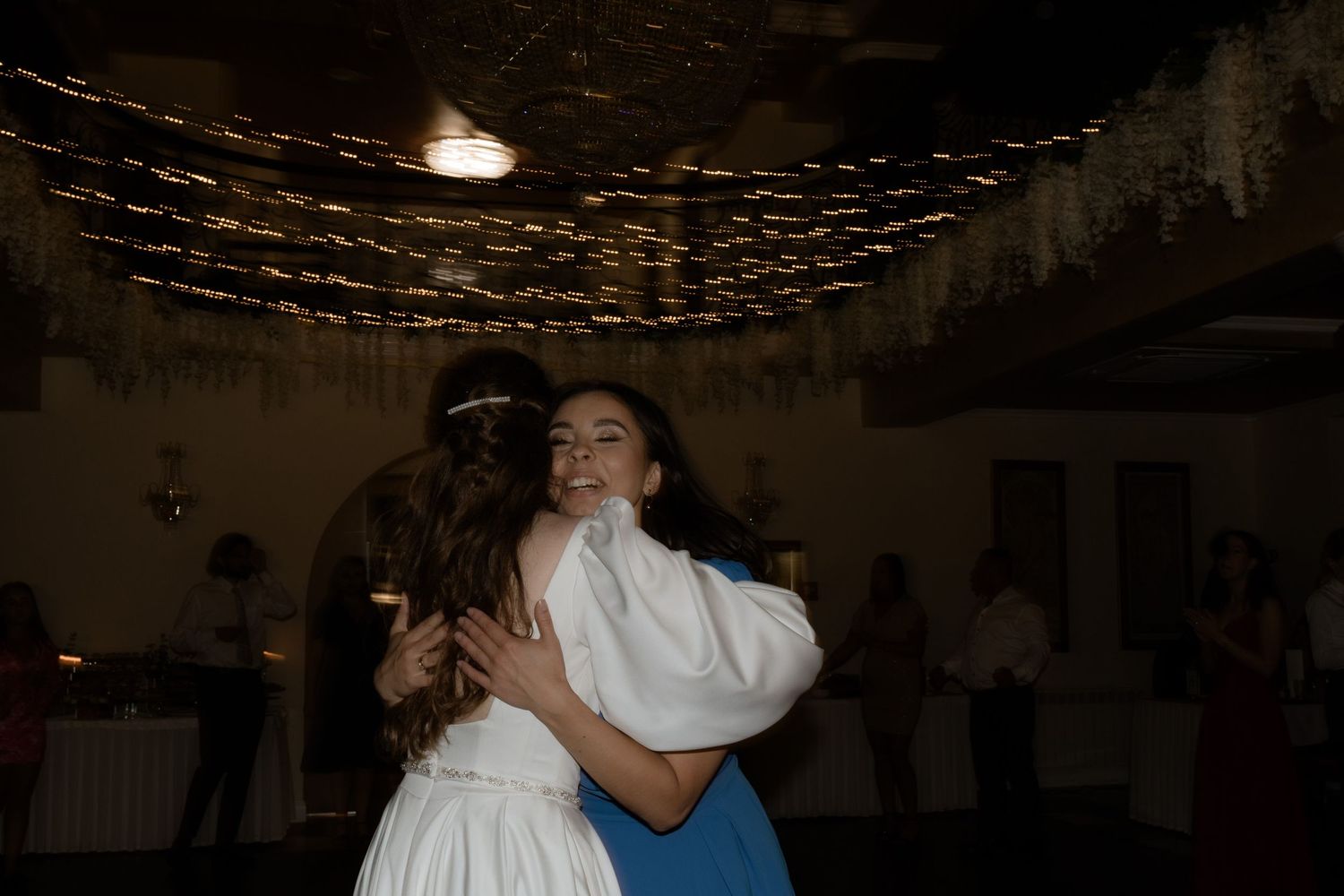 Two people sharing an intimate dance under dimly lit string lights at a wedding reception.
