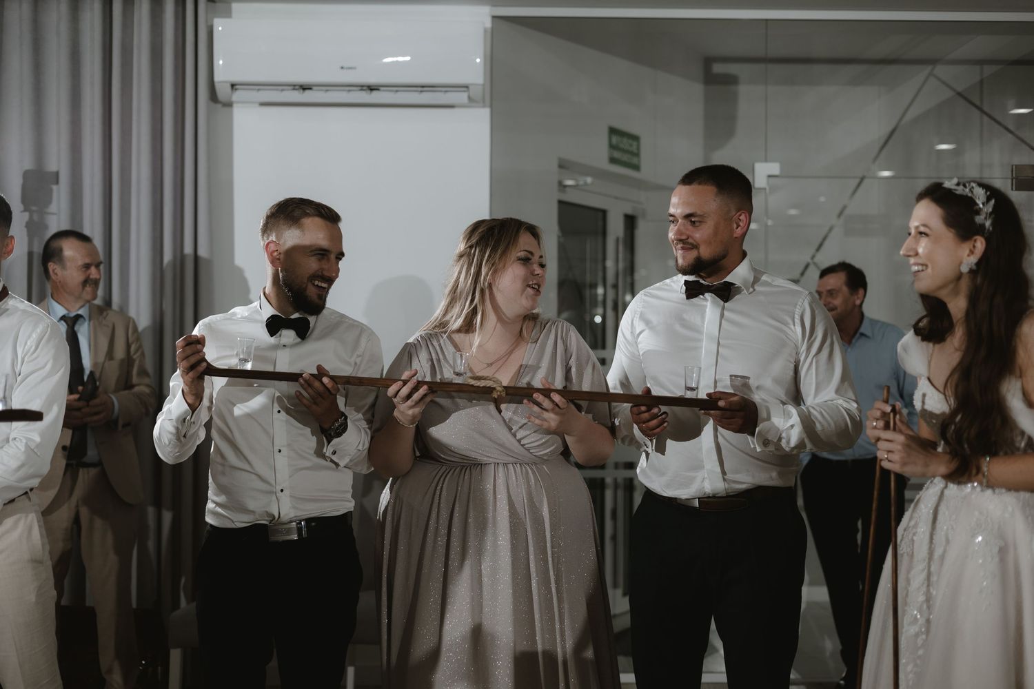 Wedding party wearing formal attire holding sparklers during an indoor celebration at a wedding reception.