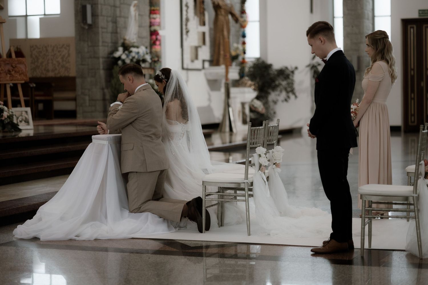 A romantic wedding ceremony scene in a church with elegant white decor and natural lighting.