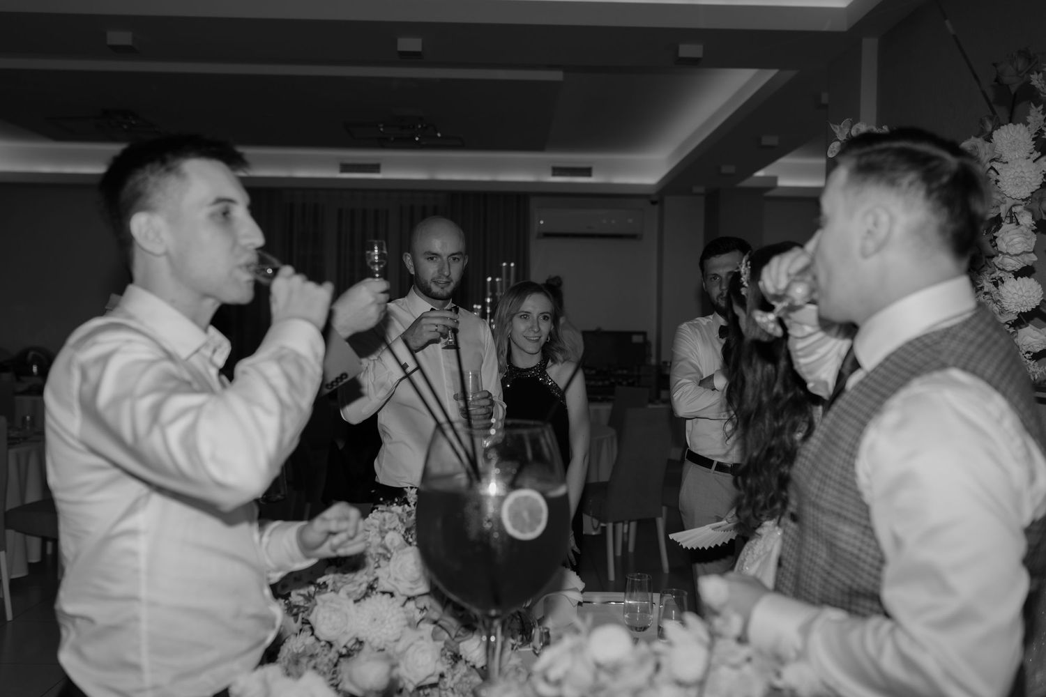 Two people sing and perform while others play saxophone at a black and white party celebration.