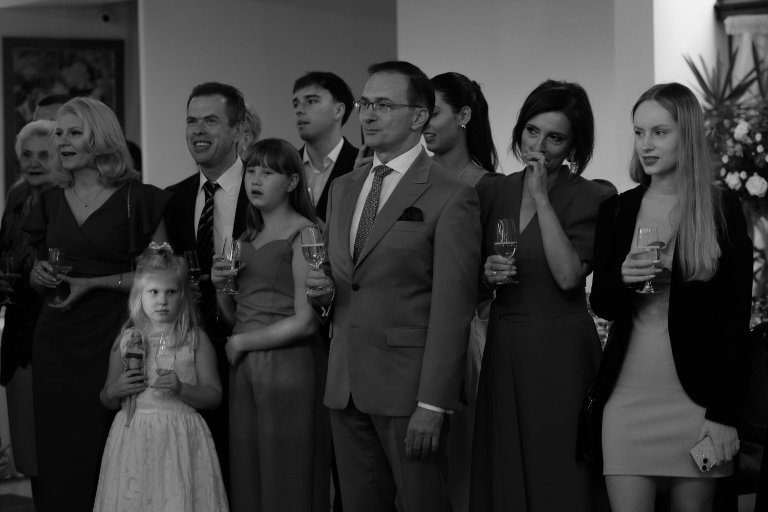 A black and white photo shows a group of people in formal attire standing together at a special event.