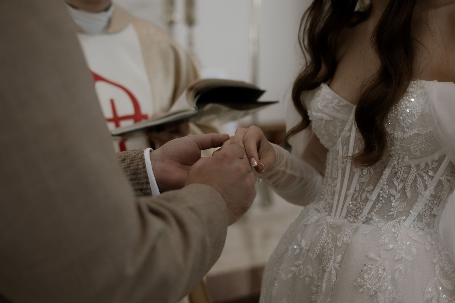 A close-up of hands during a wedding ceremony as rings are being exchanged.