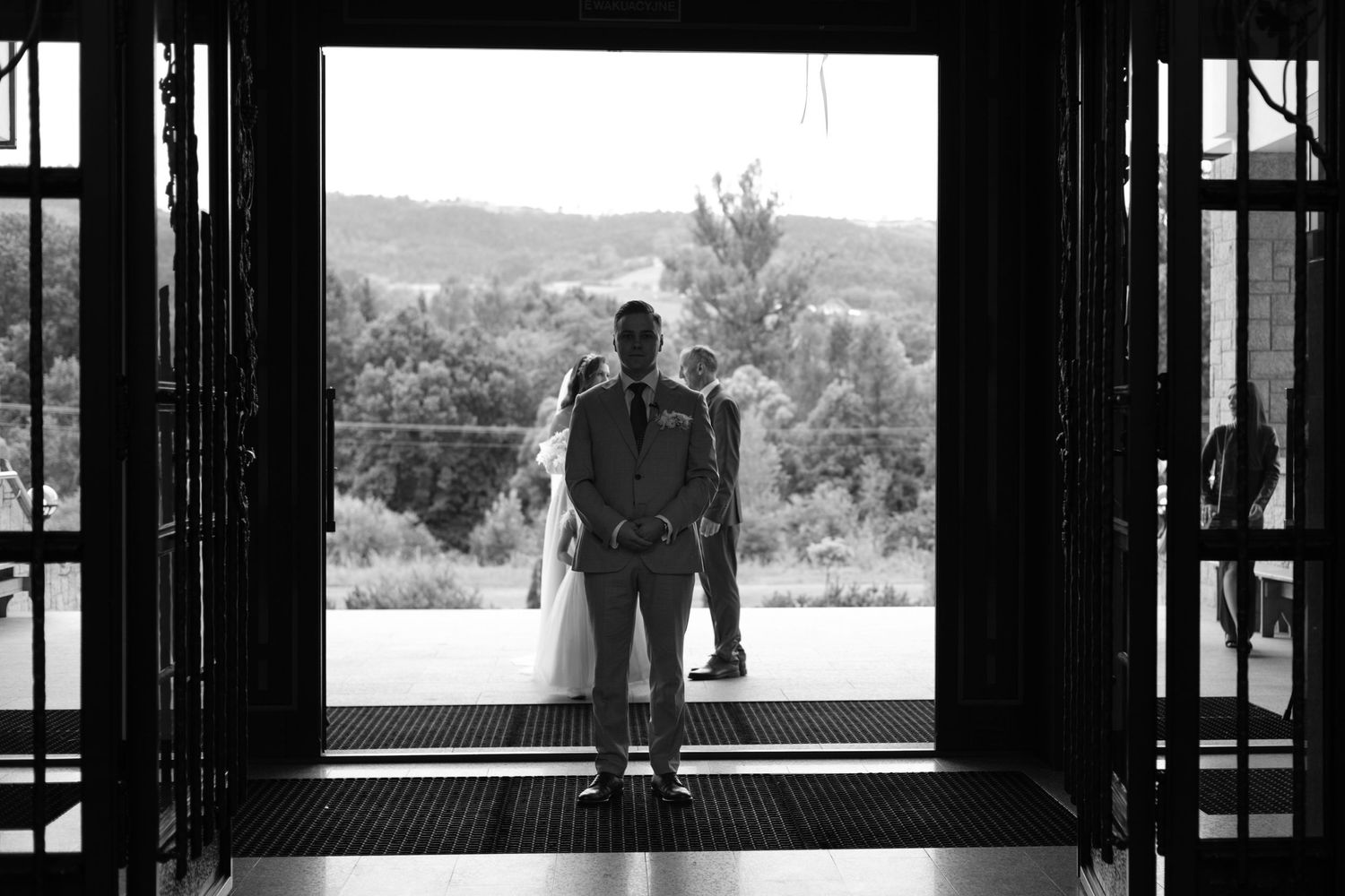 Black and white silhouette of a couple standing in doorway overlooking scenic mountain landscape view.