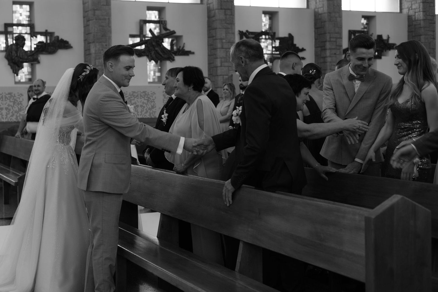 A black and white photograph of people embracing during a traditional church wedding celebration.