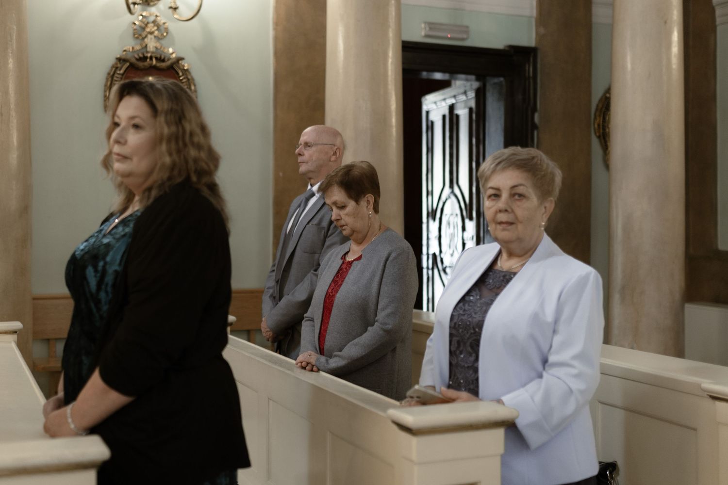 People standing in a formal hallway with columns and ornate architectural details.