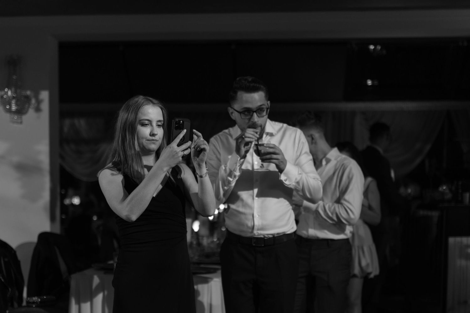 A black and white photo shows two performers singing passionately on stage in an intimate venue.