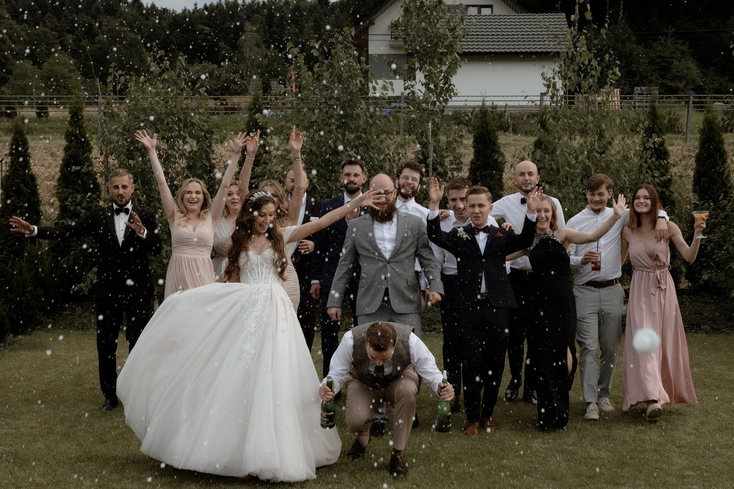 A wedding party celebrated with confetti and champagne in an outdoor garden celebration.