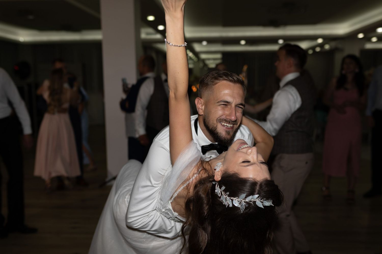 A couple shares a romantic dance moment at their wedding reception with the dancer being dipped on the dance floor.