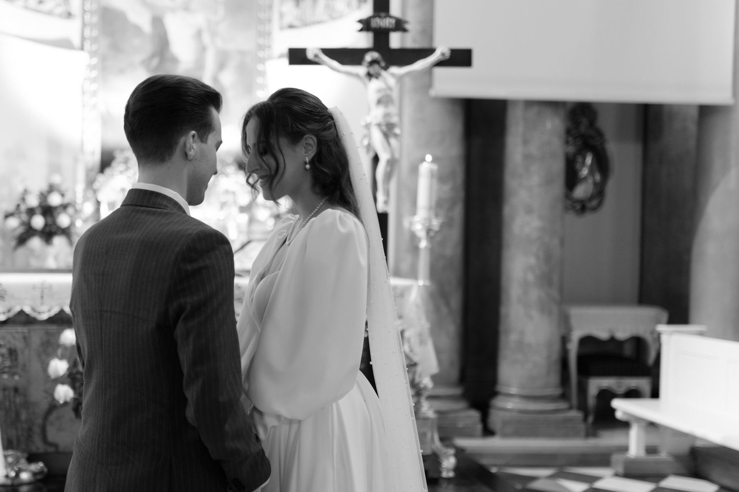 A black and white photograph shows a couple standing together at the altar during a traditional church wedding ceremony.