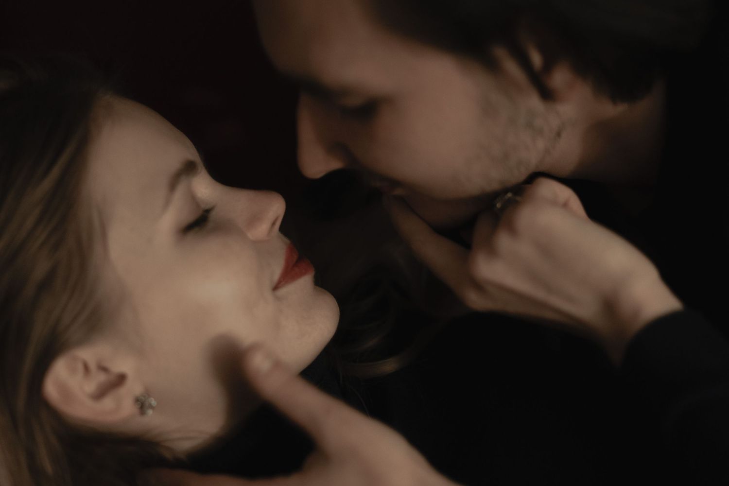 An intimate romantic scene shows a tender moment between two people in soft lighting.