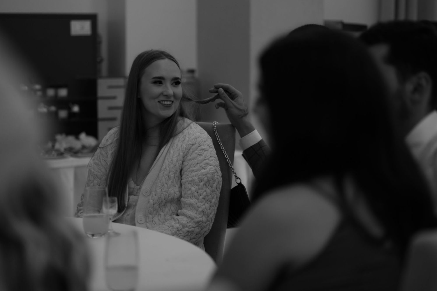 Black and white photo of a gathering showing people conversing and interacting at an indoor social event.
