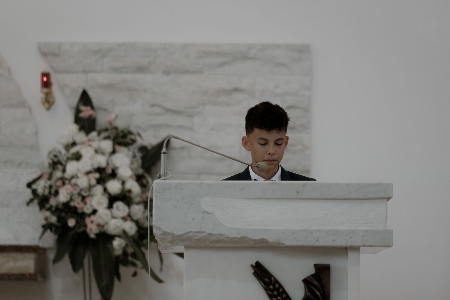 A musician plays a white piano during an elegant event decorated with pink and white floral arrangements.