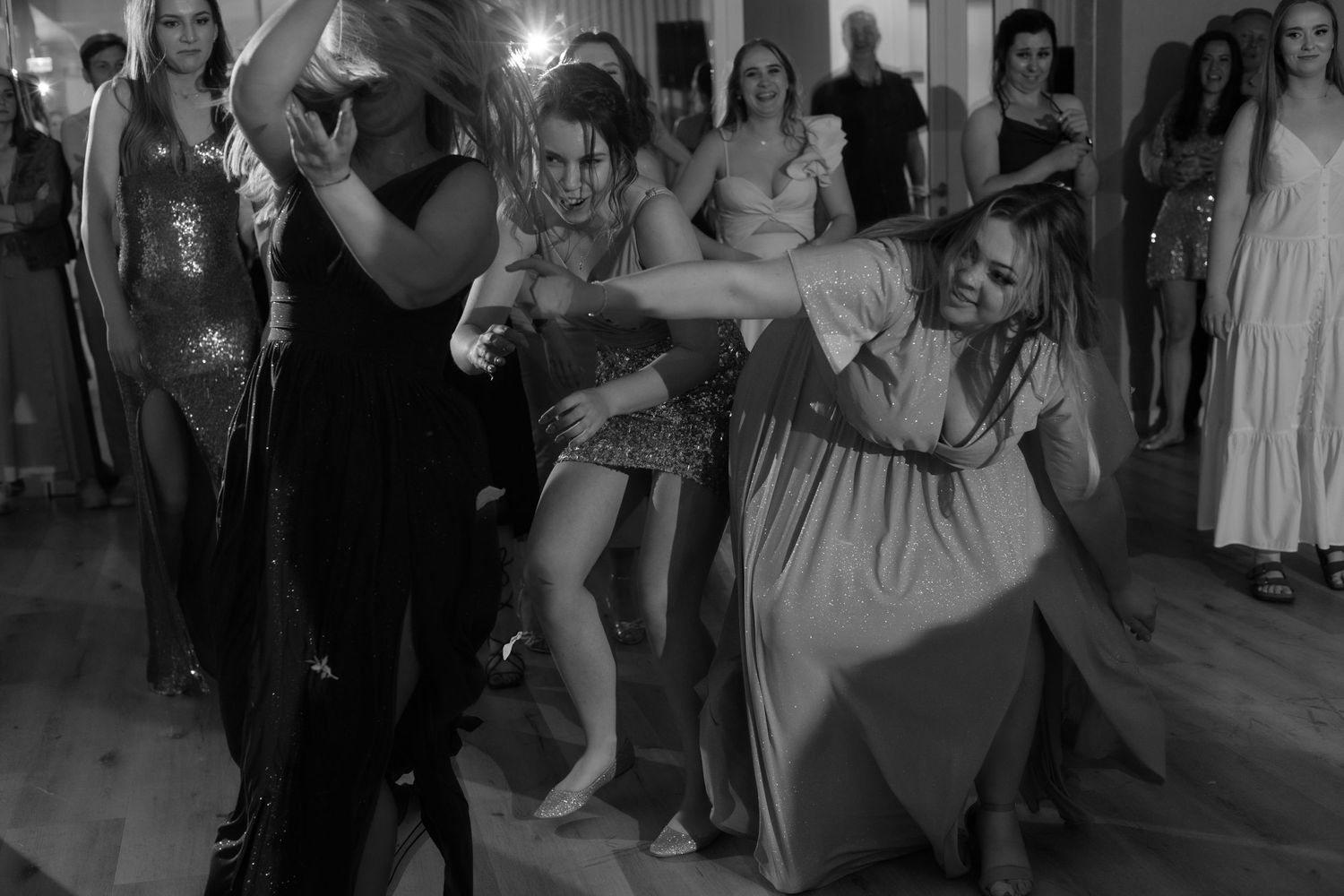 Black and white photo of people dancing energetically at what appears to be a party or celebration on a dance floor.