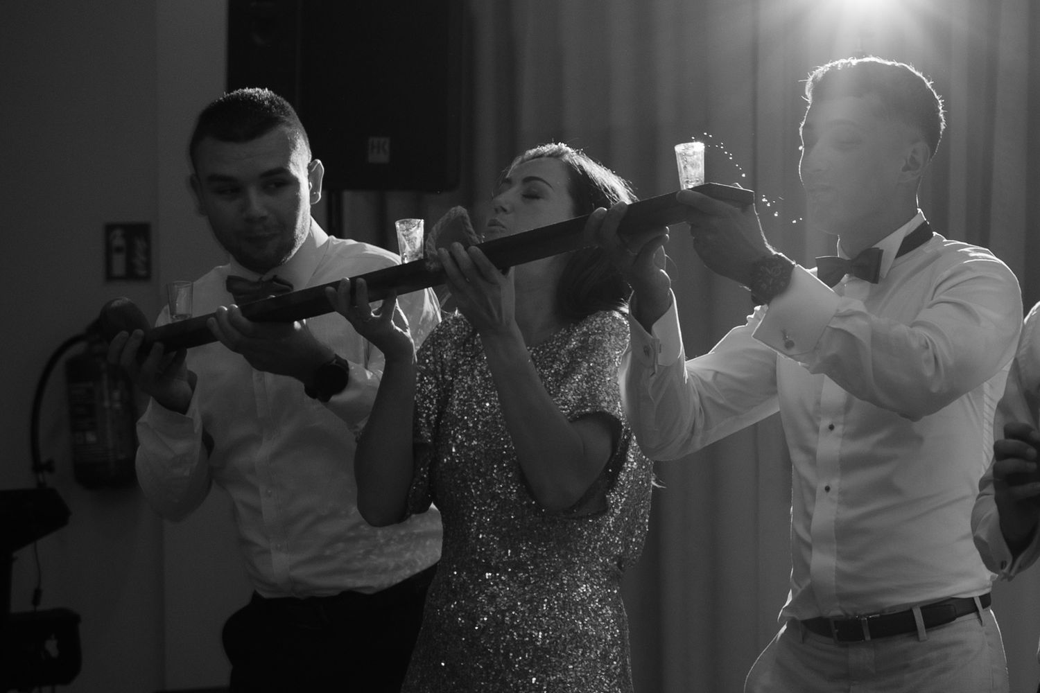 People dancing together at a celebration in black and white, with the center figure wearing a sparkly dress.