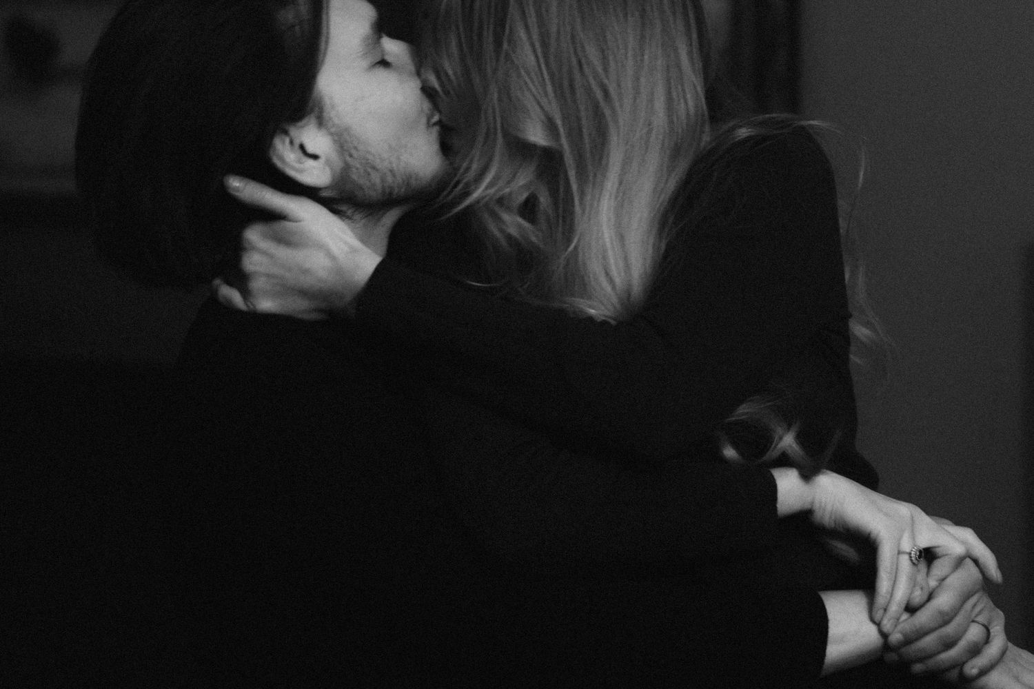 An intimate black and white photograph captures two people embracing in a tender, emotional moment.