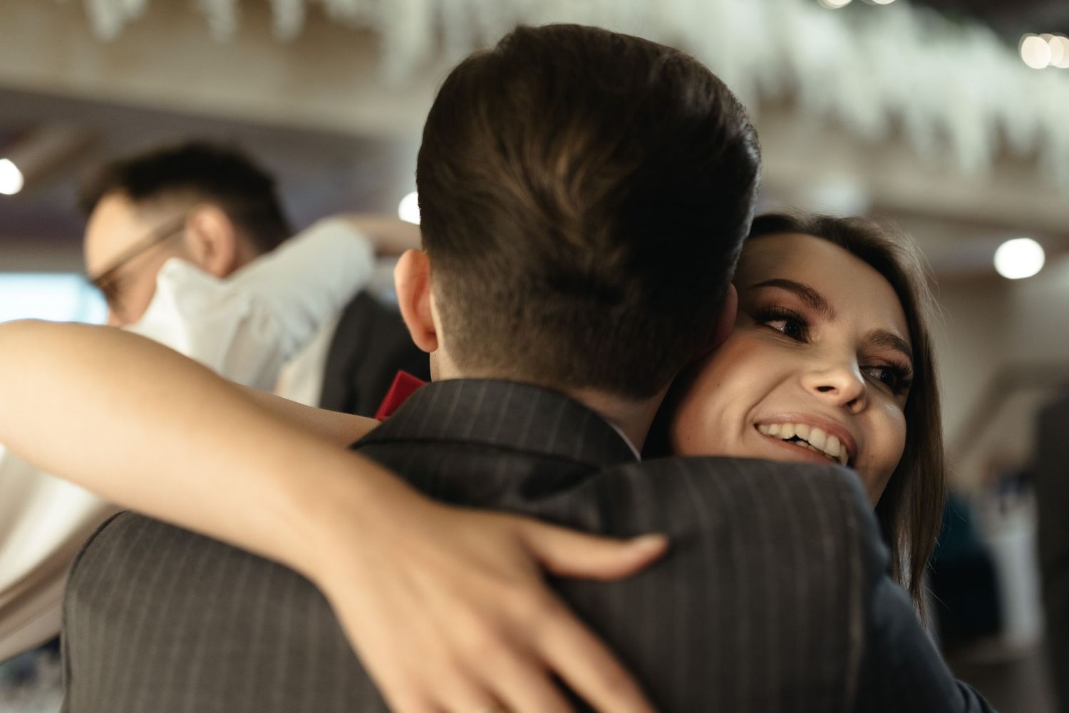 Couple embracing while slow dancing at an indoor venue with soft lighting in the background.