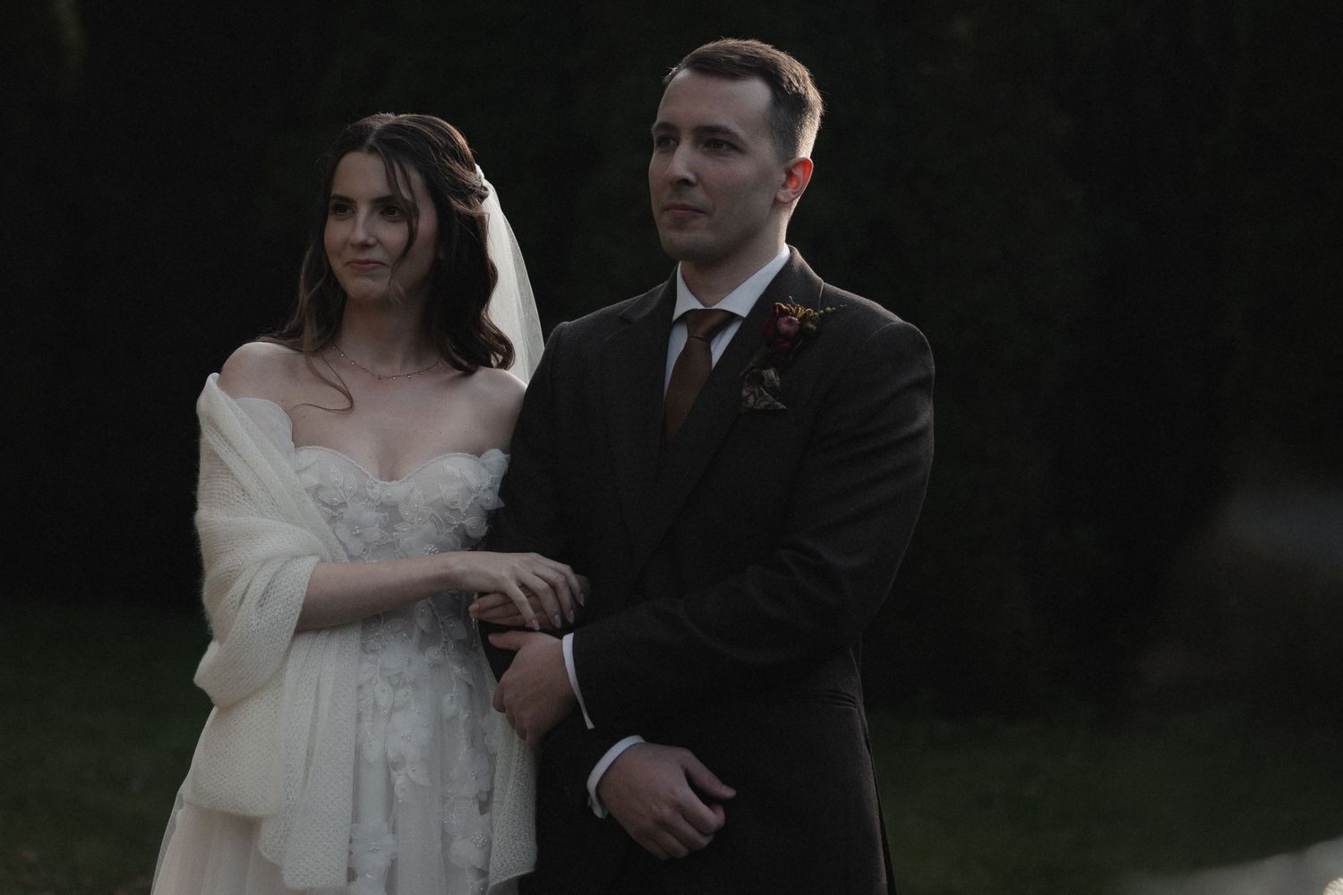 A couple in wedding attire stand together in formal poses during their outdoor wedding photo session.