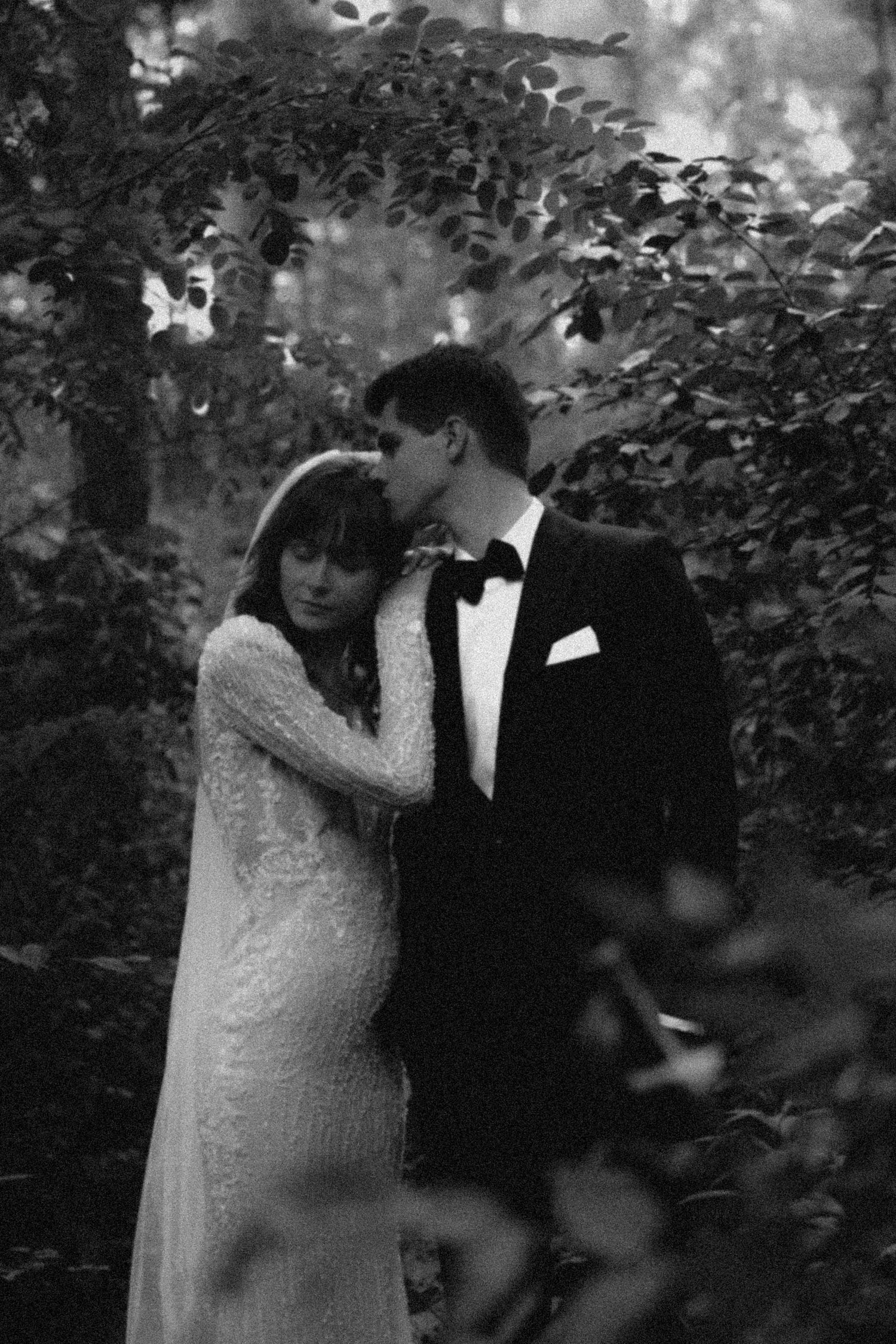 Black and white wedding photos showing a romantic moment between newlyweds in a garden setting.