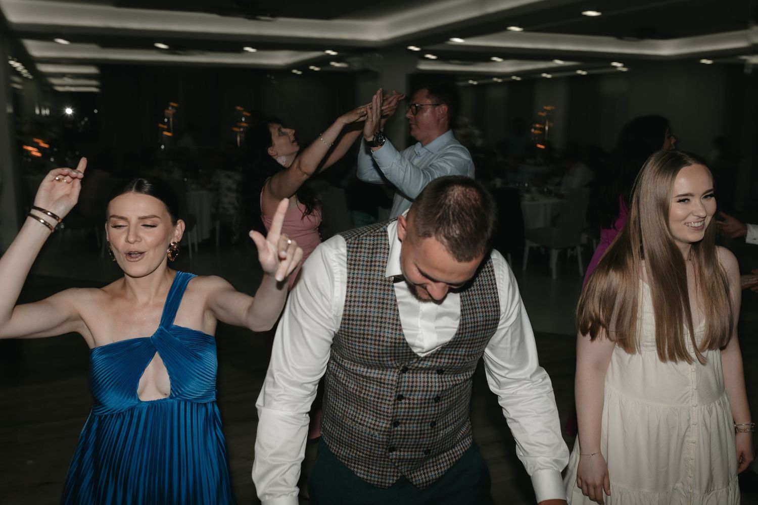 People in formal attire dancing and having fun at a festive indoor party.
