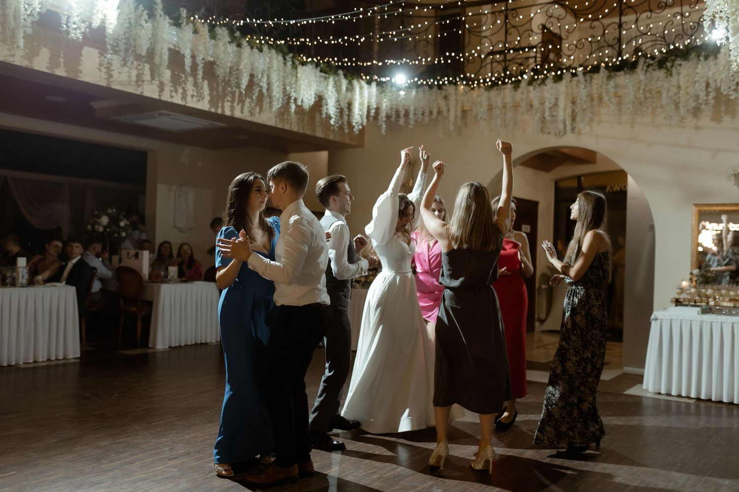 People dancing and celebrating at an elegant wedding reception with twinkle lights decorating the ceiling.