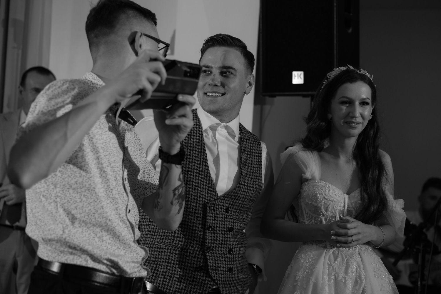 Black and white photo showing wedding guests sharing a laugh during a reception celebration.