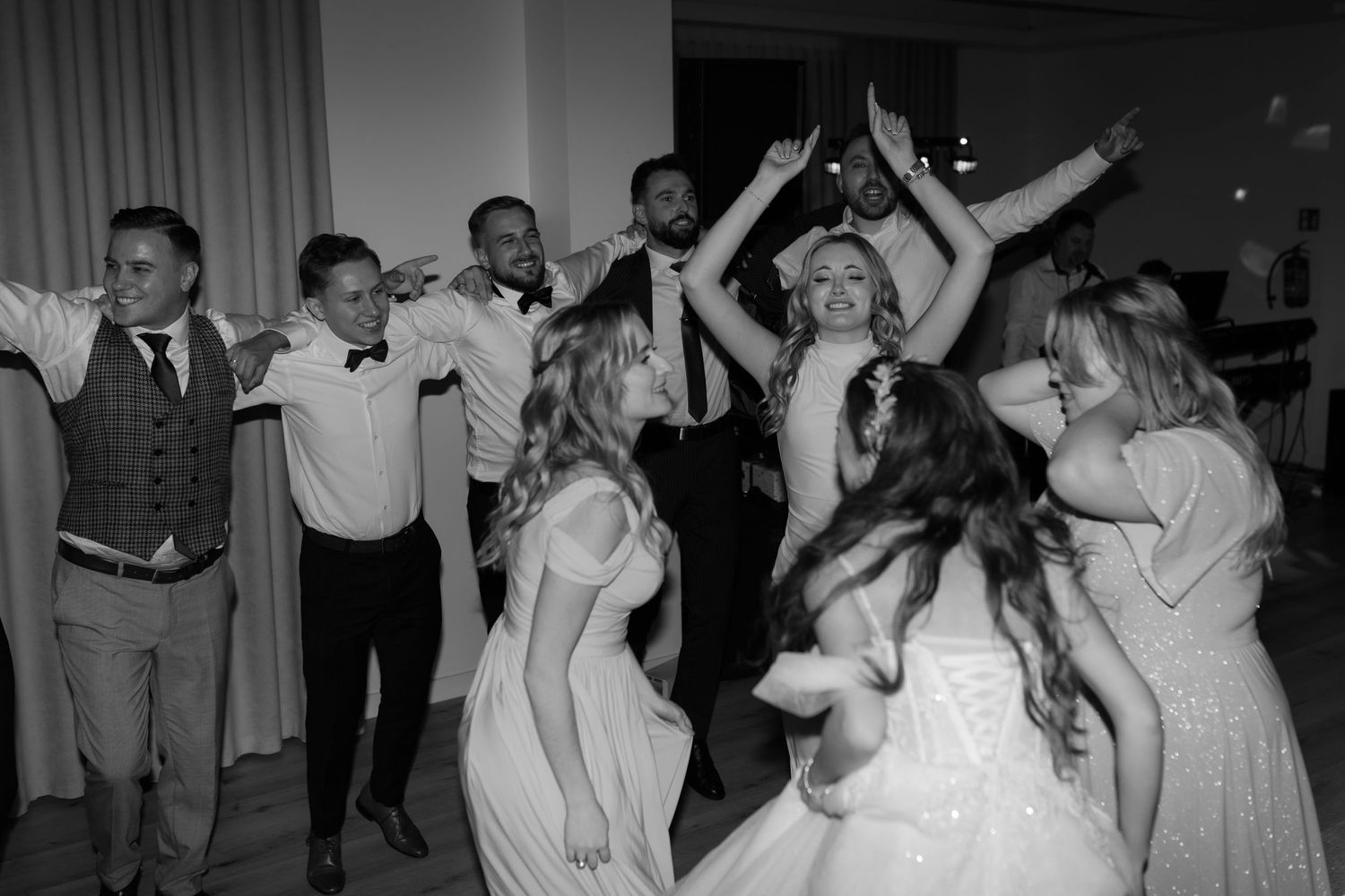 Wedding guests dancing and celebrating together at a reception in black and white photography.