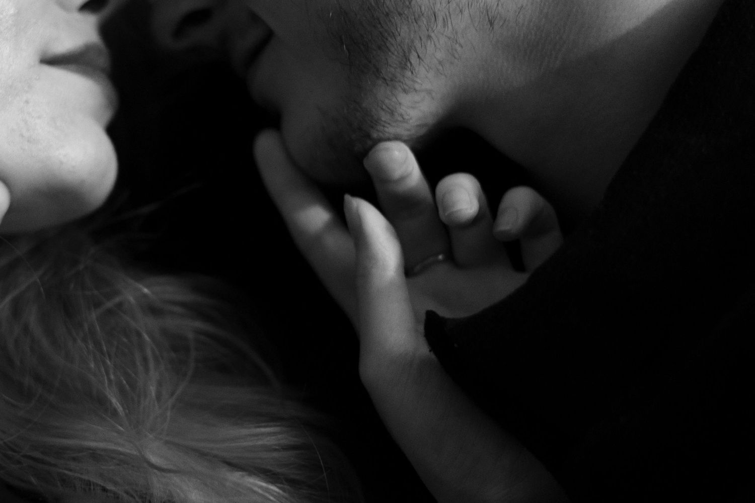A close-up black and white image shows a tender moment with two hands gently clasped together.