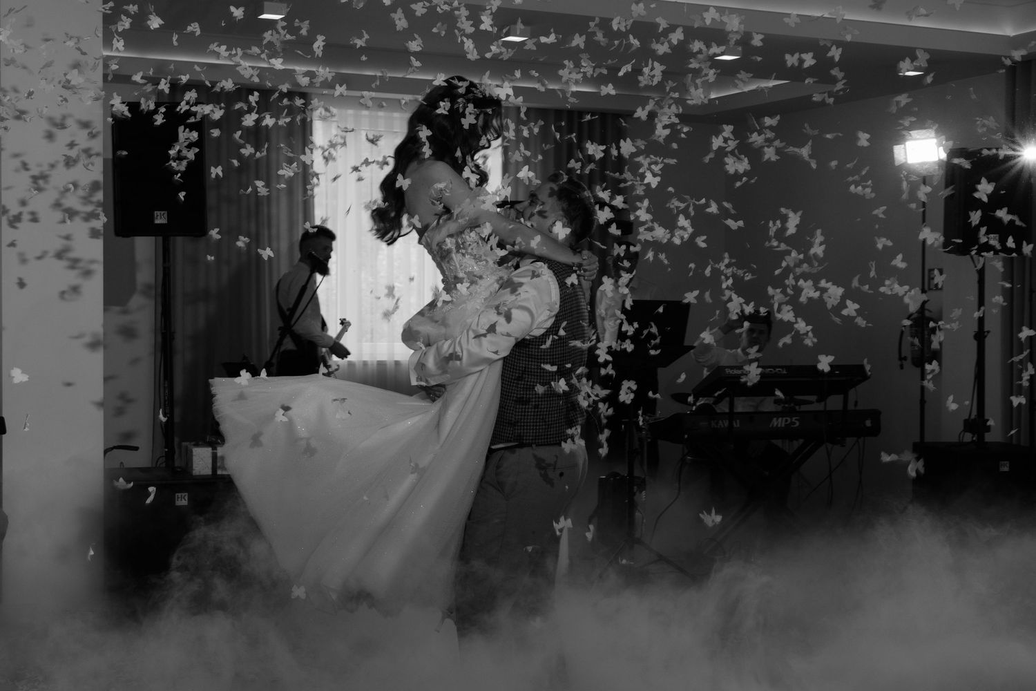 A couple dances their first dance at a wedding reception surrounded by fog and twinkling lights.