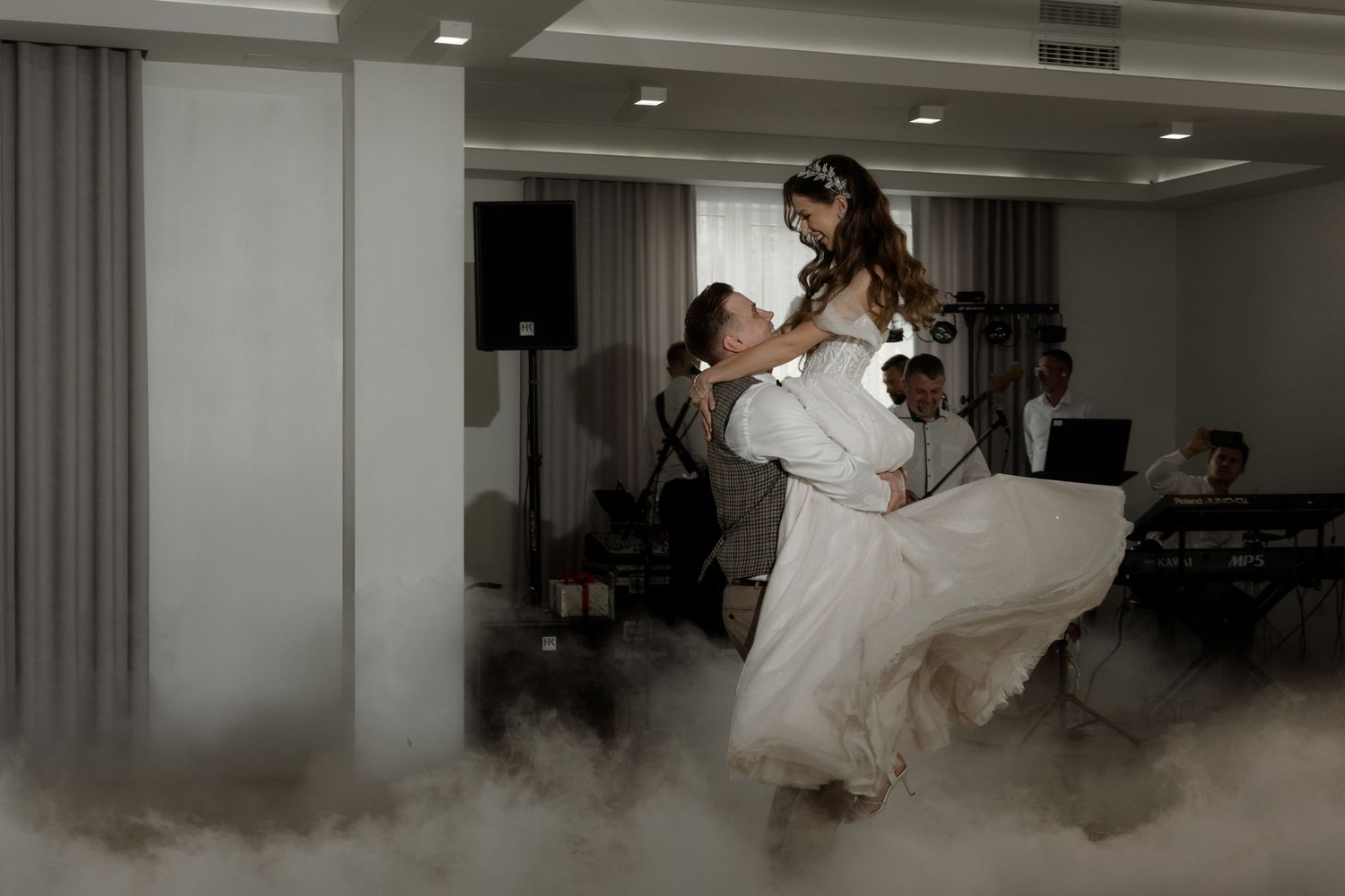 A couple performs their first dance at a wedding reception with dry ice fog swirling around their feet.