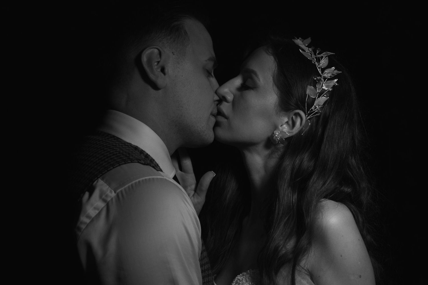 A romantic black and white wedding photograph capturing an intimate kiss between newlyweds.