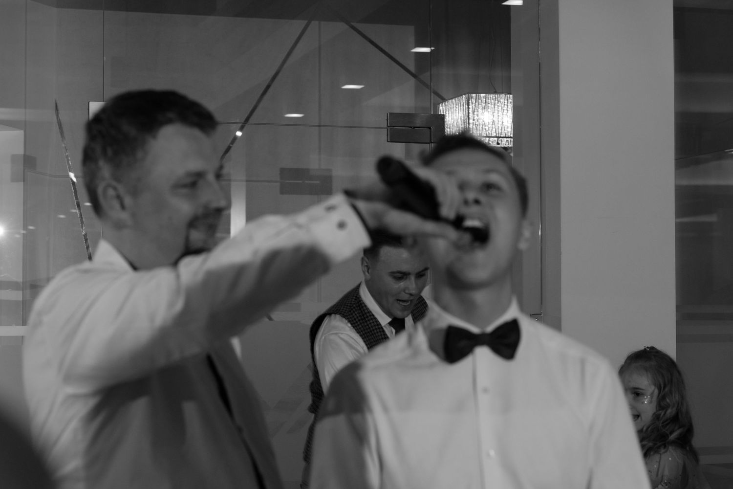 A fun moment captured in black and white as someone playfully feeds cake to another person wearing a bow tie.
