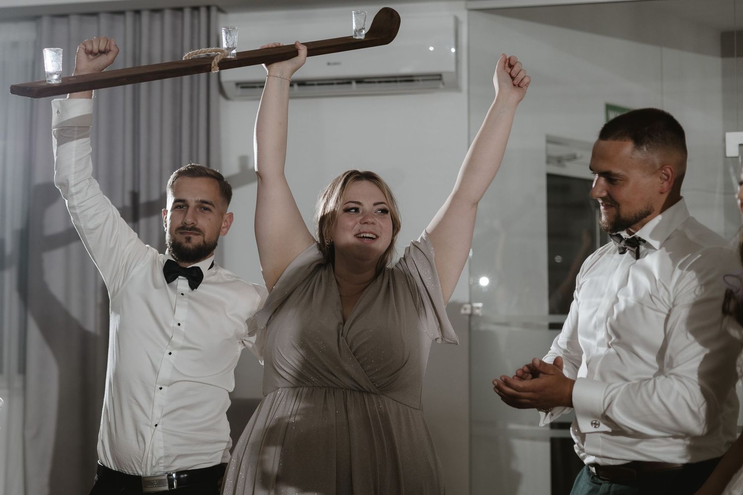 Celebratory scene at a party with three guests raising their arms in joyful excitement.