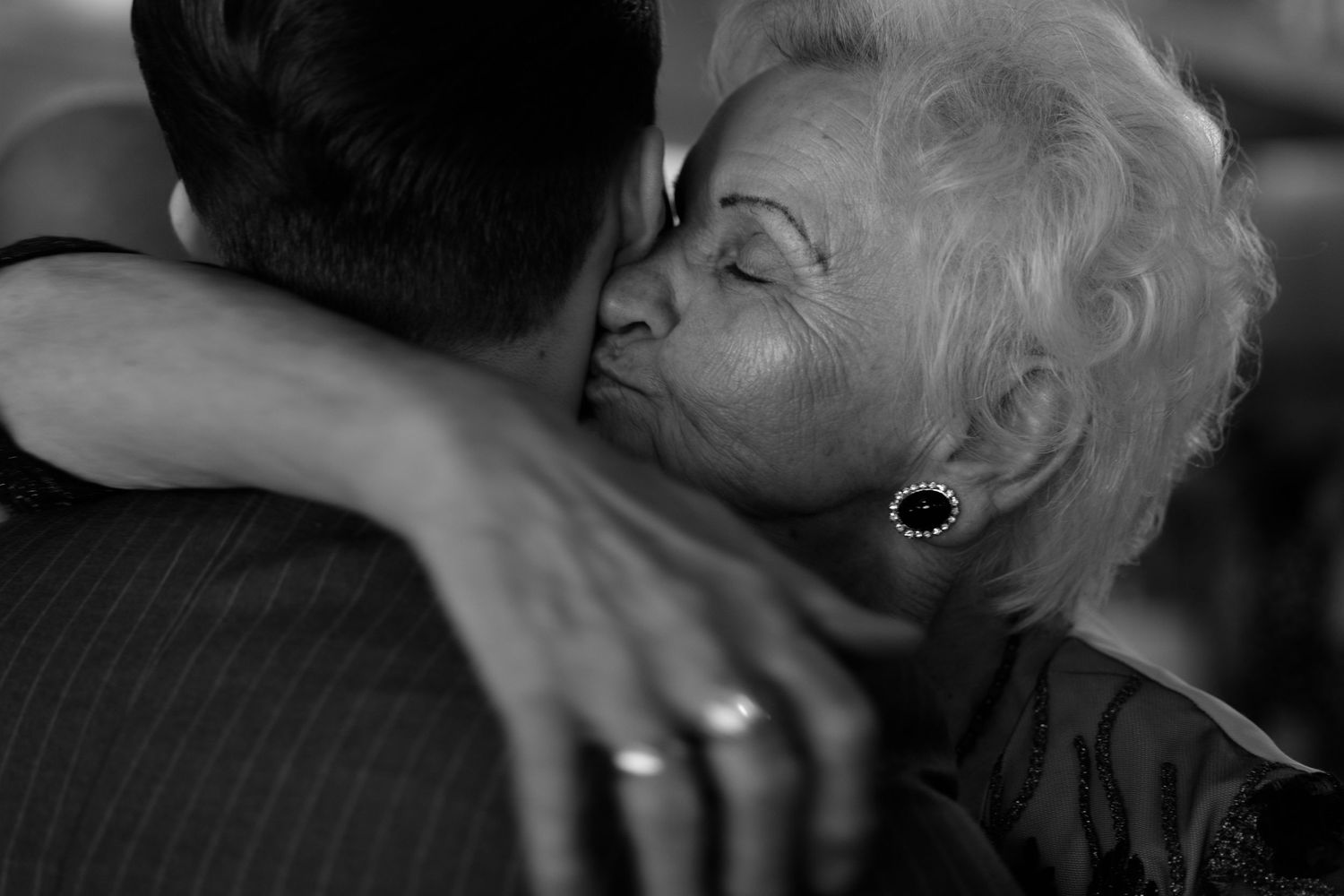 A tender black and white photograph capturing an intimate embrace between dancers, with visible wedding rings.