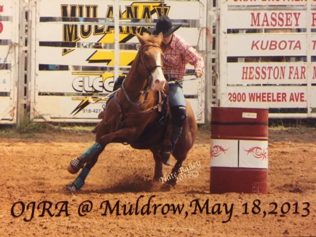 Western barrel racer competes on horseback around a turn at the Muldrow OJRA rodeo event in 2013.