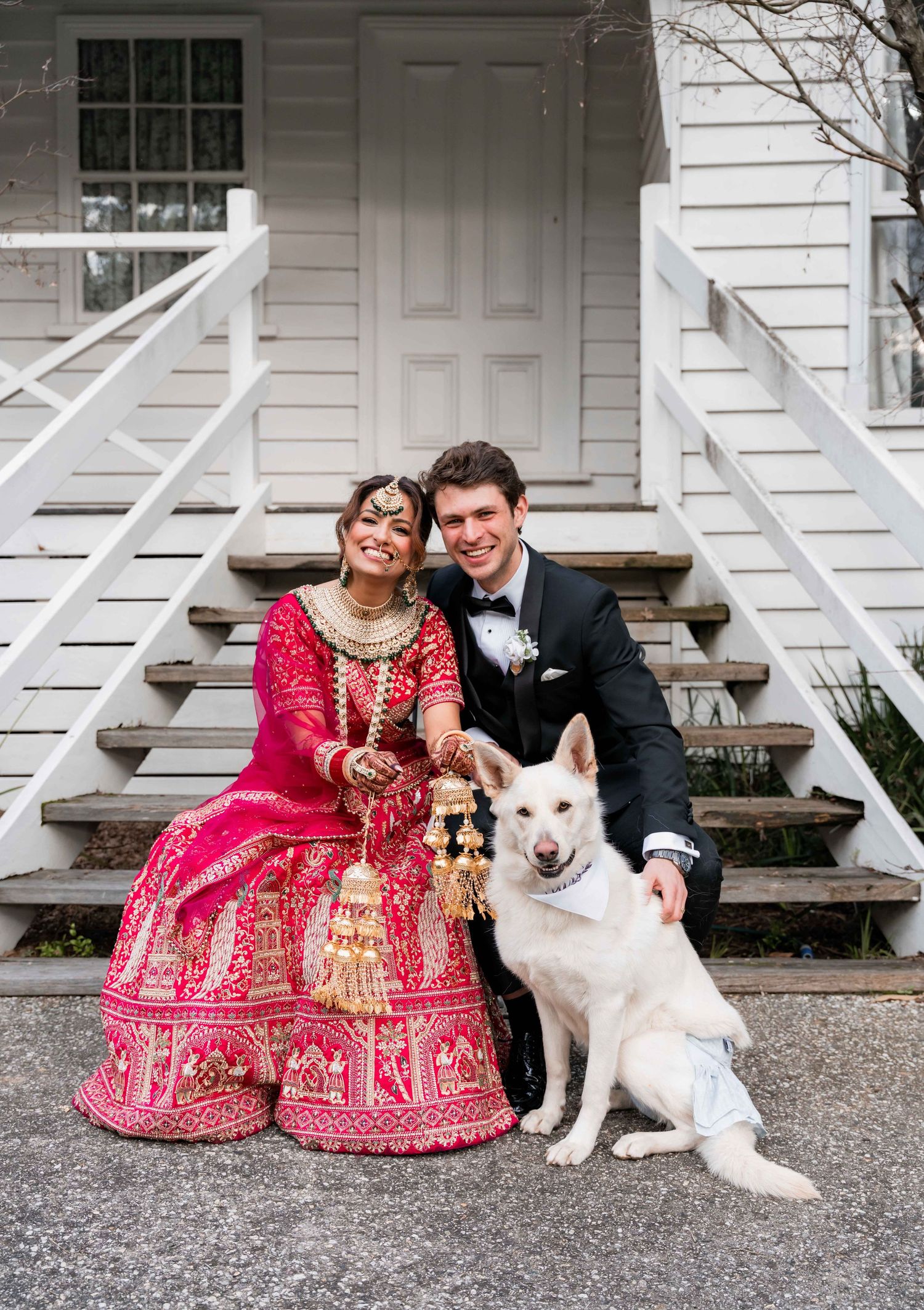 A couple in traditional wedding attire sits on porch steps with their white dog in a series of casual portraits.