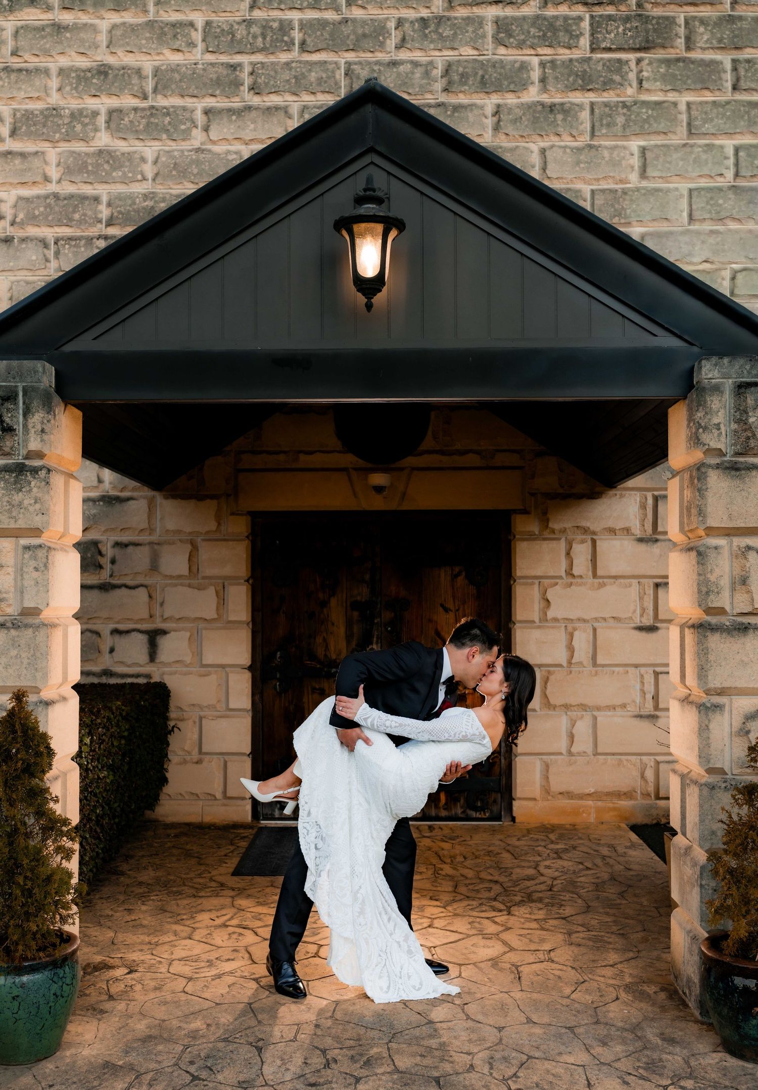 A romantic dip dance sequence in front of a brick wall and garage entrance illuminated by warm outdoor lighting.