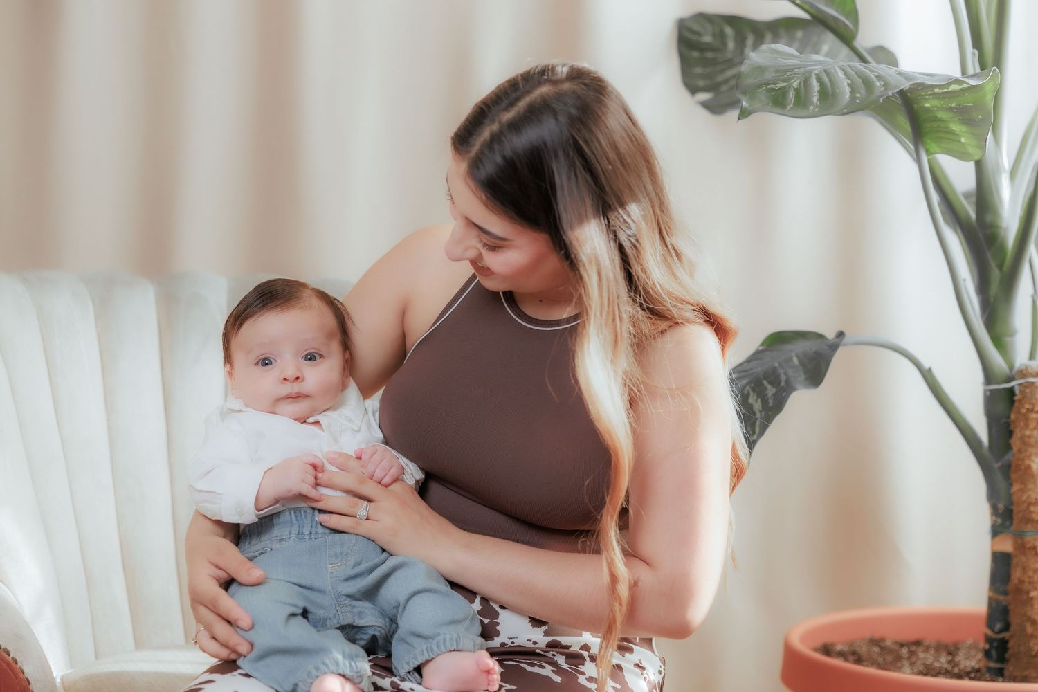 Mother holding her baby during a bright indoor family photography session with soft natural light.