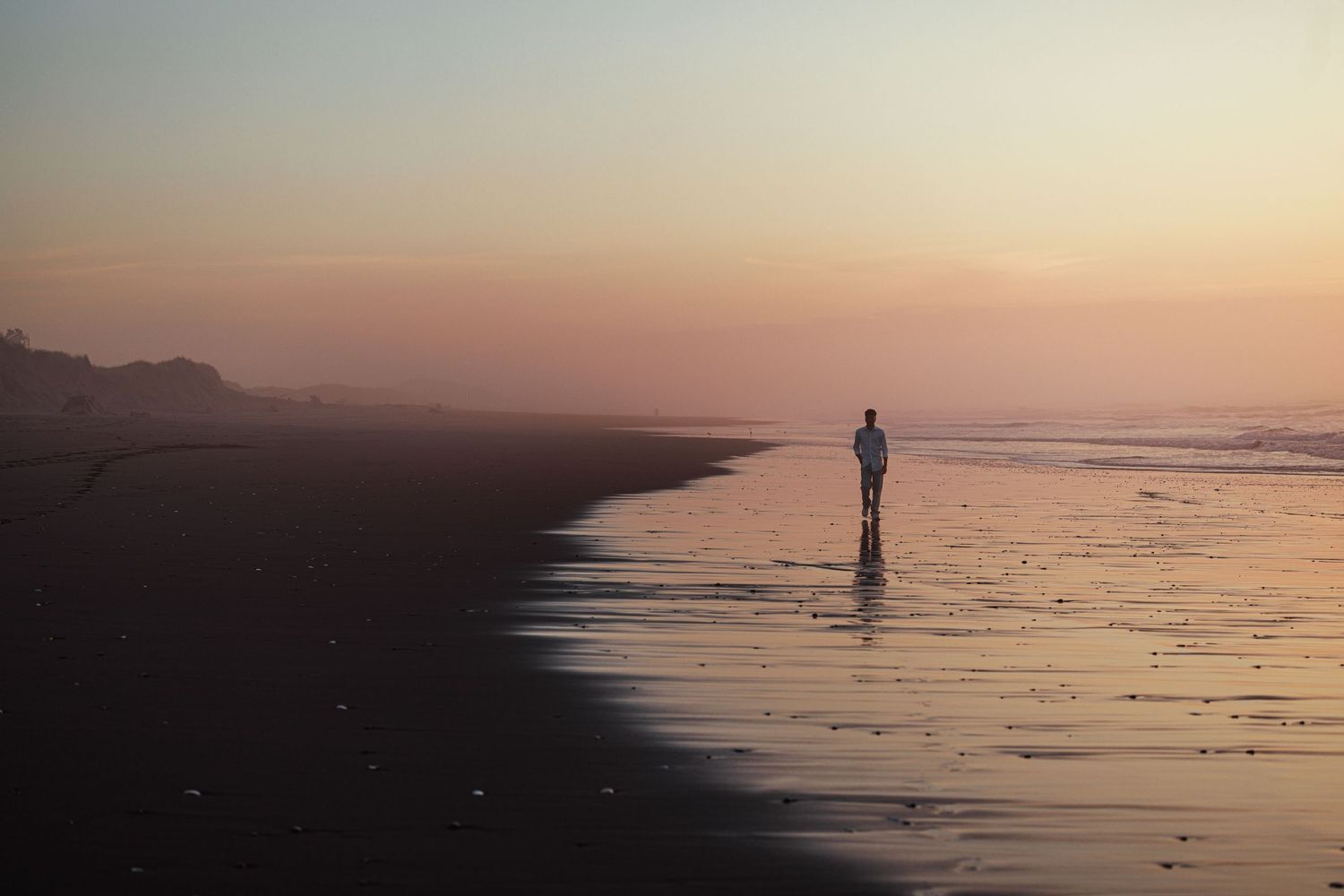 High school senior standing along the ocean shoreline at sunset during a dramatic coastal portrait session.