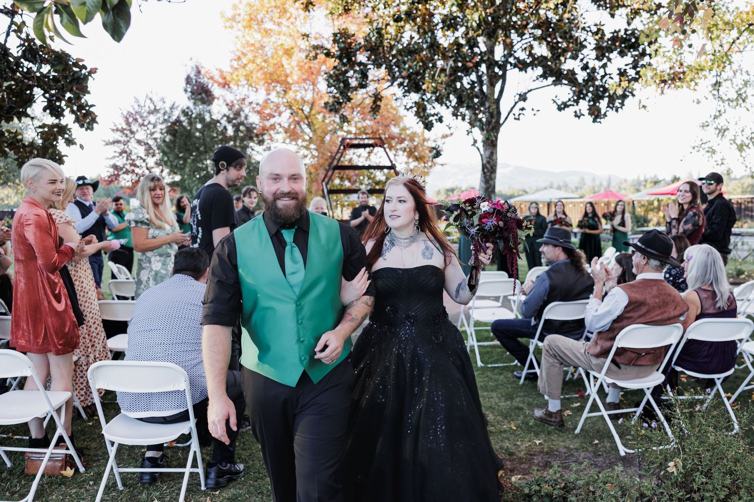 Newlyweds smile while walking back down the aisle after their outdoor wedding ceremony.