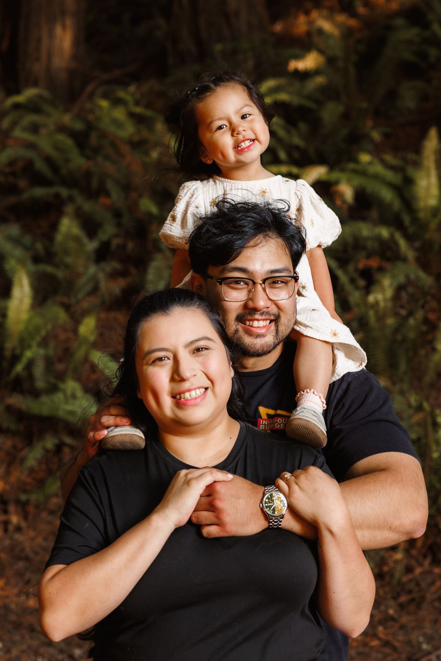 Father holding smiling child on his shoulders during outdoor family session