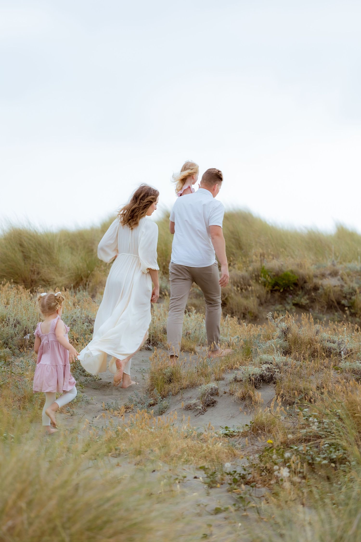 Family walking together through grassy field during golden-hour session