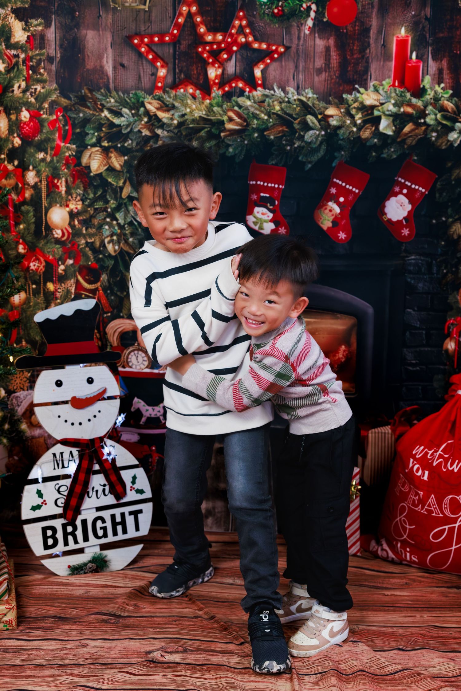 Young boy posing for a Christmas portrait in front of festive red and black holiday decorations.