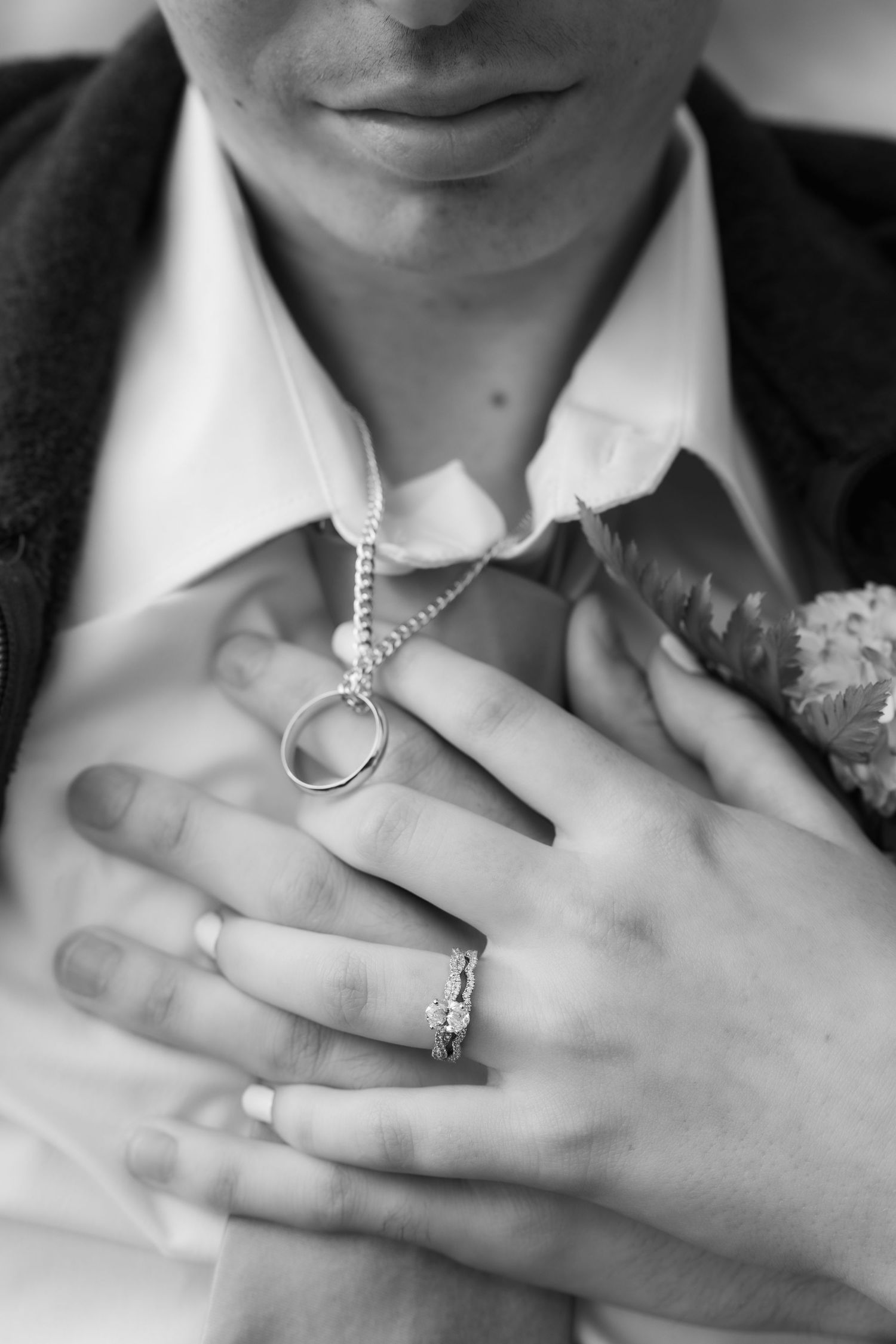 Close-up of a wedding couple’s hands resting together against the groom’s suit.