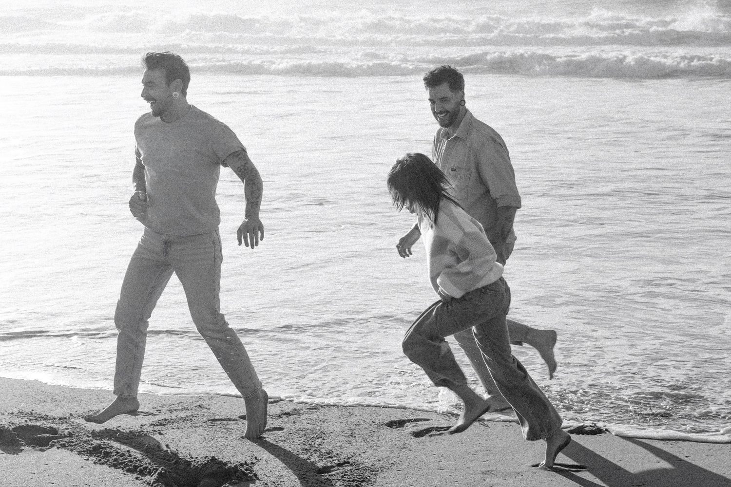 Black and white candid photo of a family walking and playing together along the Northern California coast.